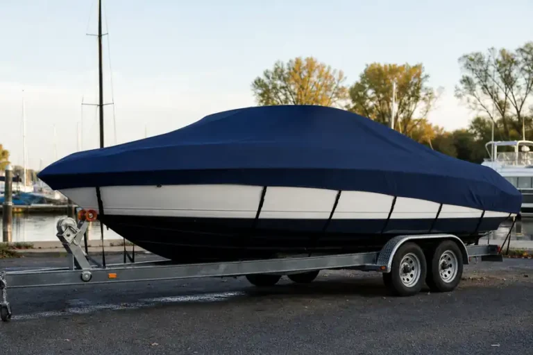 Trailored boat with a snug dark navy cover and straps in a marina lot