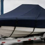 Covered trailered boat with support straps creating a sloped ridge line to reduce water pooling