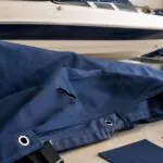 Damaged navy boat cover being assessed for repair in a marine workshop