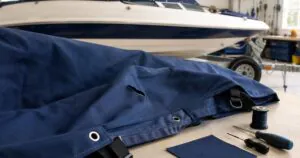 Damaged navy boat cover being assessed for repair in a marine workshop