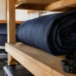 Clean dark marine boat cover loosely rolled on an elevated shelf with straps organized nearby